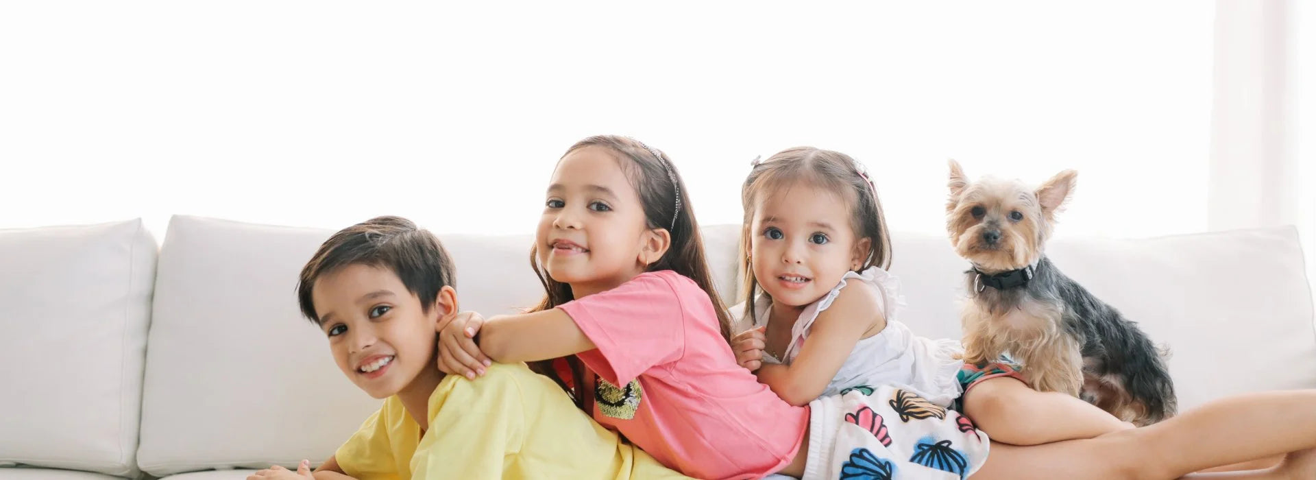 Kids and dog playing on sofa in a fresh and odor-free home environment.